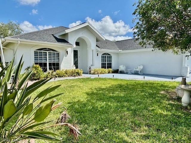 Ranch-style house with a front yard, stucco siding, and roof with shingles