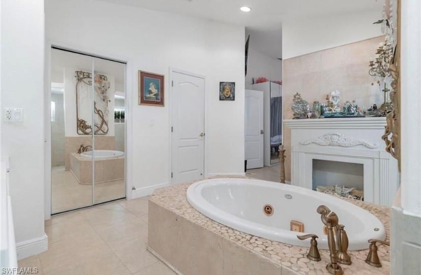 Full bath with a whirlpool tub, light tile patterned flooring, vanity, and recessed lighting