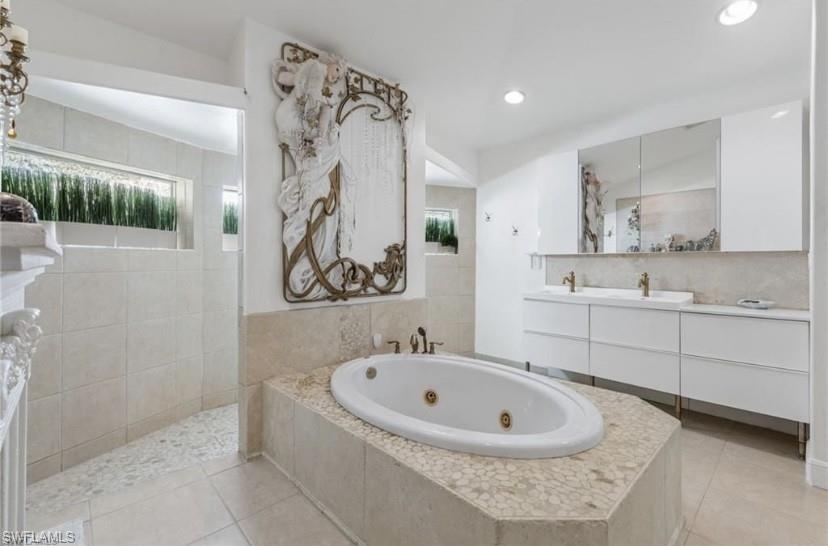 Full bath with vanity, a whirlpool tub, walk through shower, and light tile patterned floors