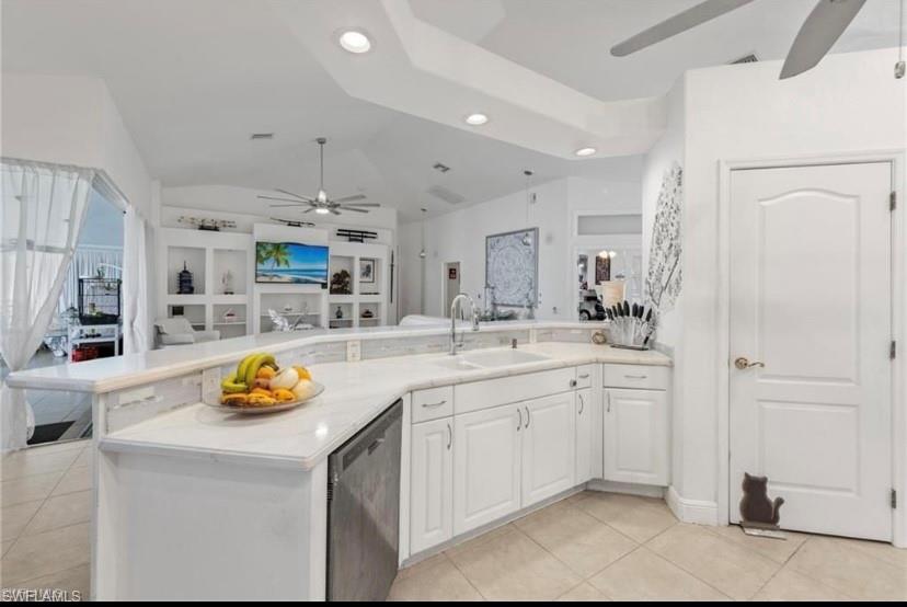 Kitchen with ceiling fan, open floor plan, white cabinetry, dishwasher, and light tile patterned flooring