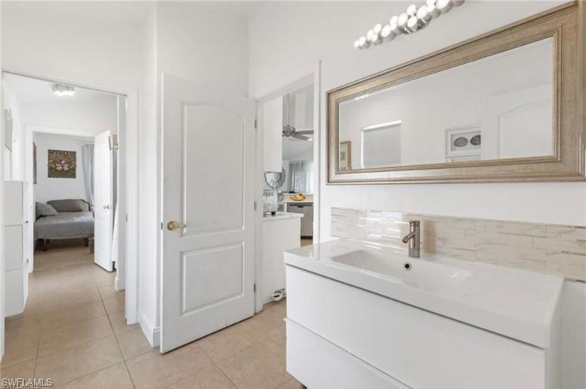 Bathroom in guest suite/ with vanity, decorative backsplash, ensuite bath, and light tile patterned floors
