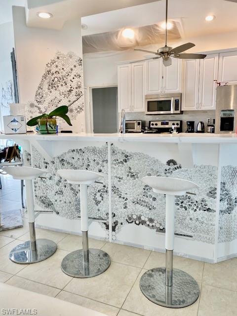 Kitchen featuring white cabinetry, recessed lighting, a breakfast bar area, a ceiling fan, and stainless steel appliances