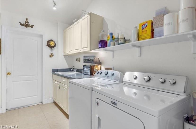 Laundry room featuring separate washer and dryer, cabinet space, and light tile patterned floors