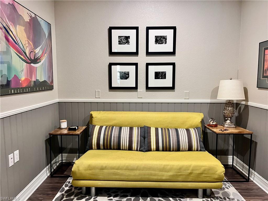 Sitting area with queen pullout featuring dark wood-style flooring and a wainscoted wall perfect for reading a book.