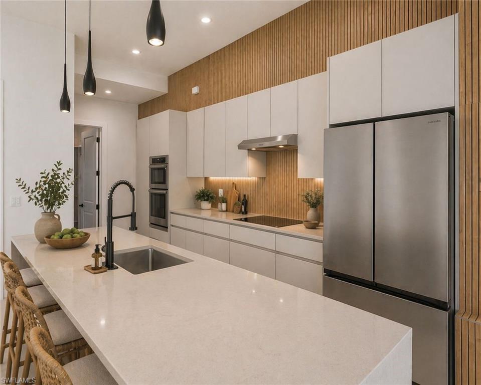 Gourmet kitchen featuring a large island with an undermount sink, a matte black faucet, and pendant lighting