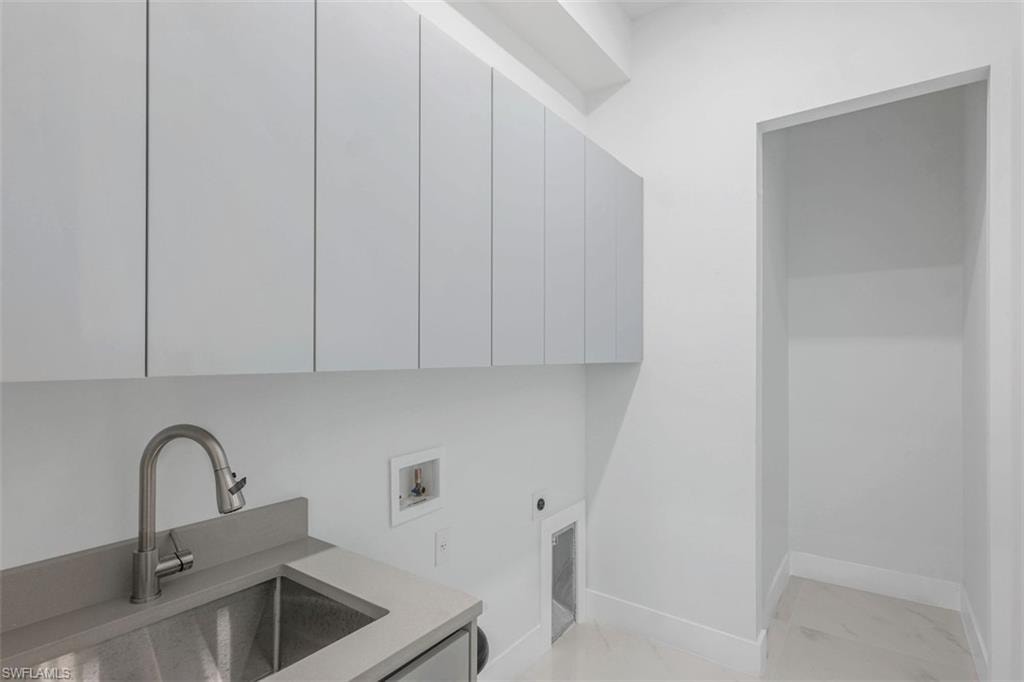 Laundry area featuring a stainless steel utility sink, pull-down faucet, and gray countertop