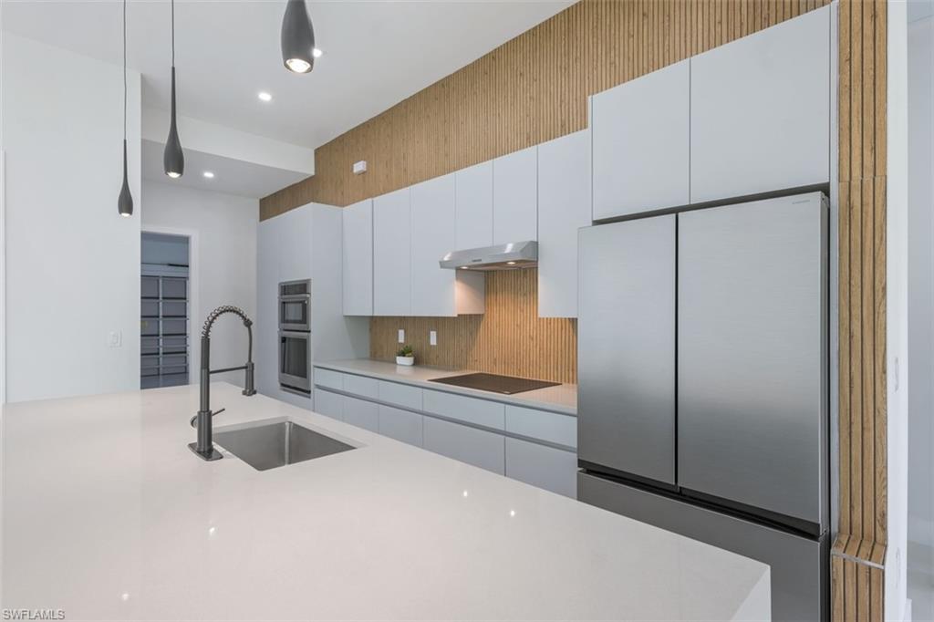 Kitchen featuring an expansive white countertop island with an undermount sink and matte black pull-down faucet