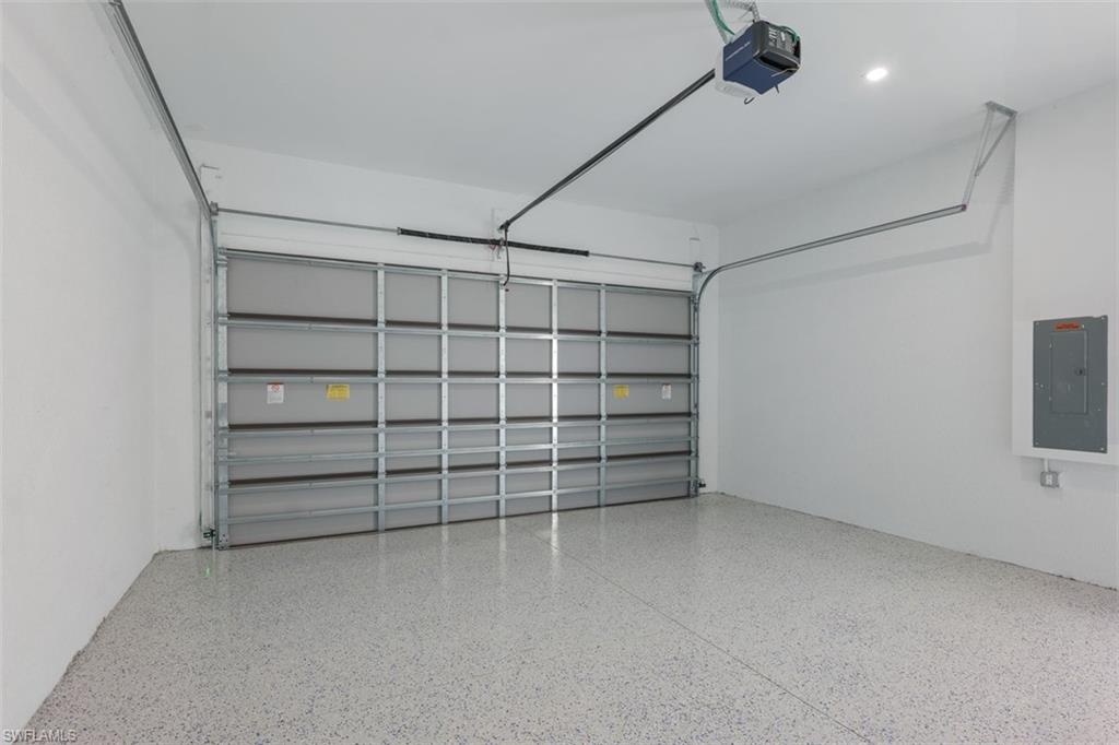 Spacious garage featuring a sectional garage door, light-colored epoxy flooring, and recessed lighting