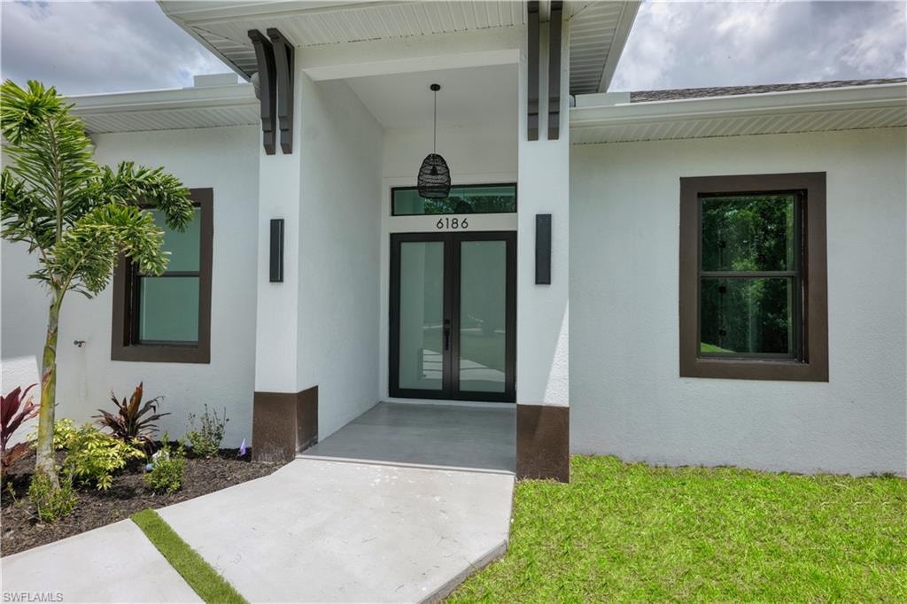Contemporary exterior featuring a covered entry, dark-framed impact-resistant windows, and a glass-paneled double-door entry