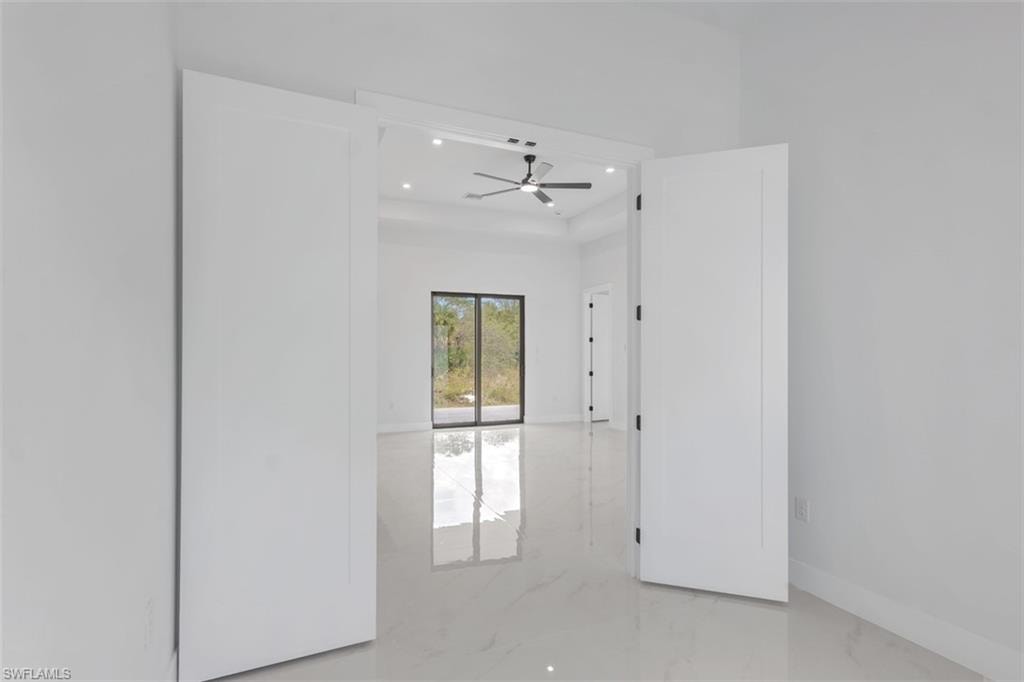 Double panel doors opening into a spacious room with high ceilings, recessed lighting, and a contemporary ceiling fan