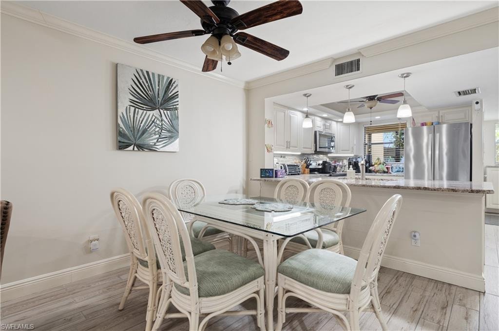 Dining room with crown molding, a ceiling fan, and light wood-style flooring