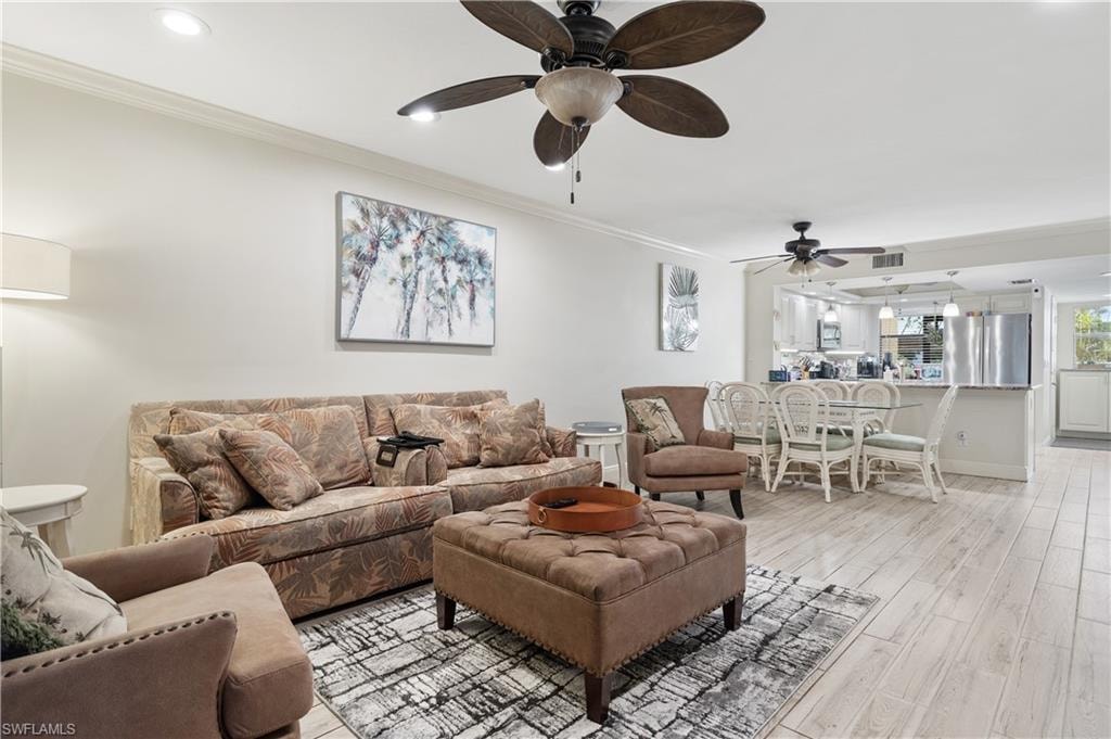 Living area featuring ornamental molding, light wood-type flooring, a ceiling fan, and recessed lighting