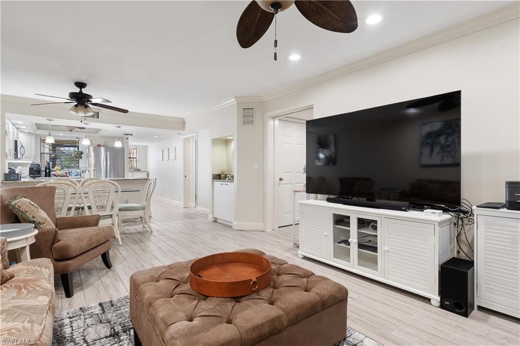 Living room with ceiling fan, crown molding, light wood finished floors, and recessed lighting