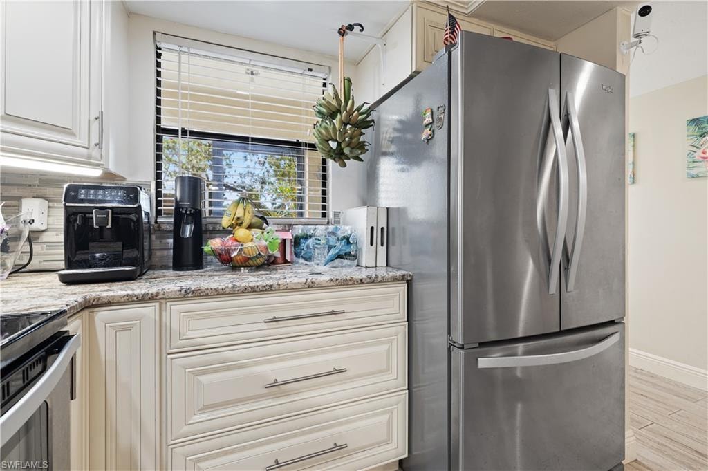Kitchen featuring stainless steel appliances, light stone counters, light wood finished floors, and white cabinets