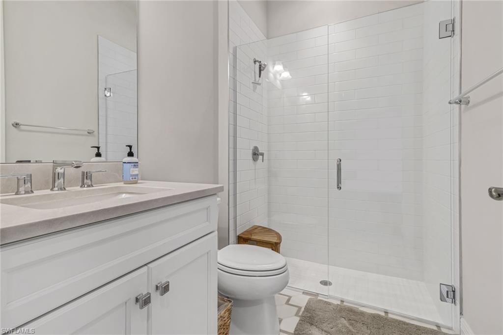 Bathroom featuring a stall shower, toilet, and vanity