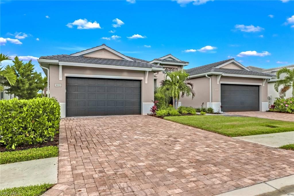 Single story home with decorative driveway, an attached garage, and stucco siding