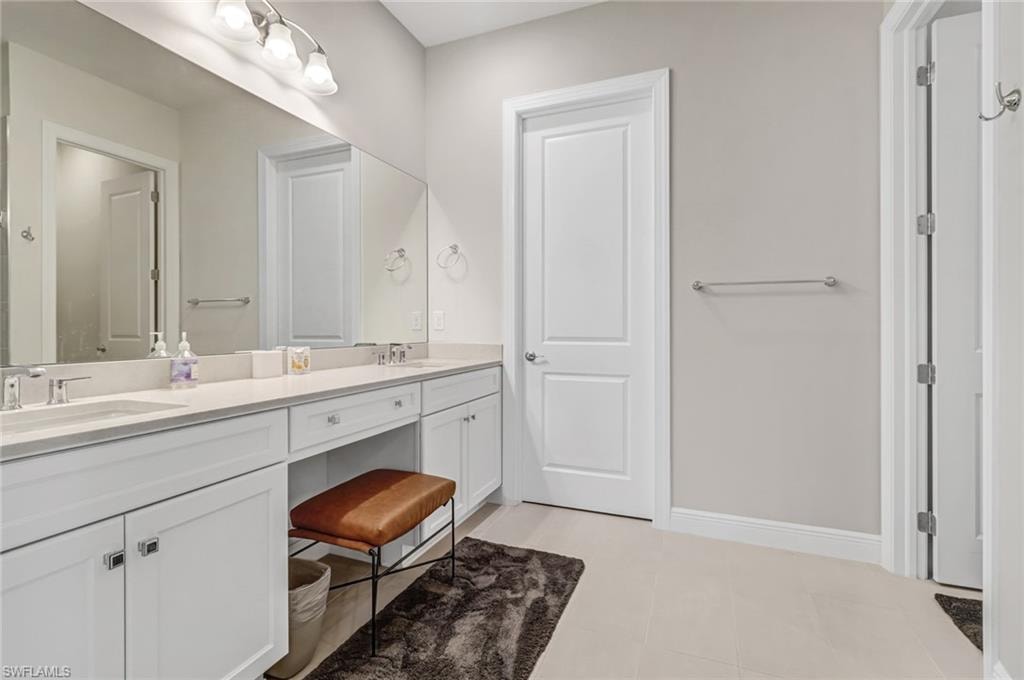 Bathroom featuring a sink, baseboards, double vanity, and tile patterned flooring