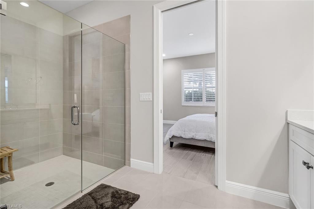 Ensuite bathroom featuring a stall shower, recessed lighting, connected bathroom, baseboards, and vanity