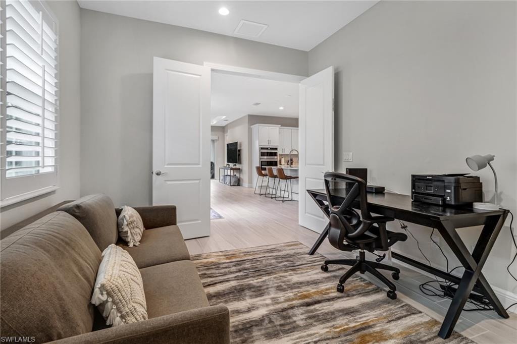 Home office featuring light wood-style flooring, recessed lighting, and a sink