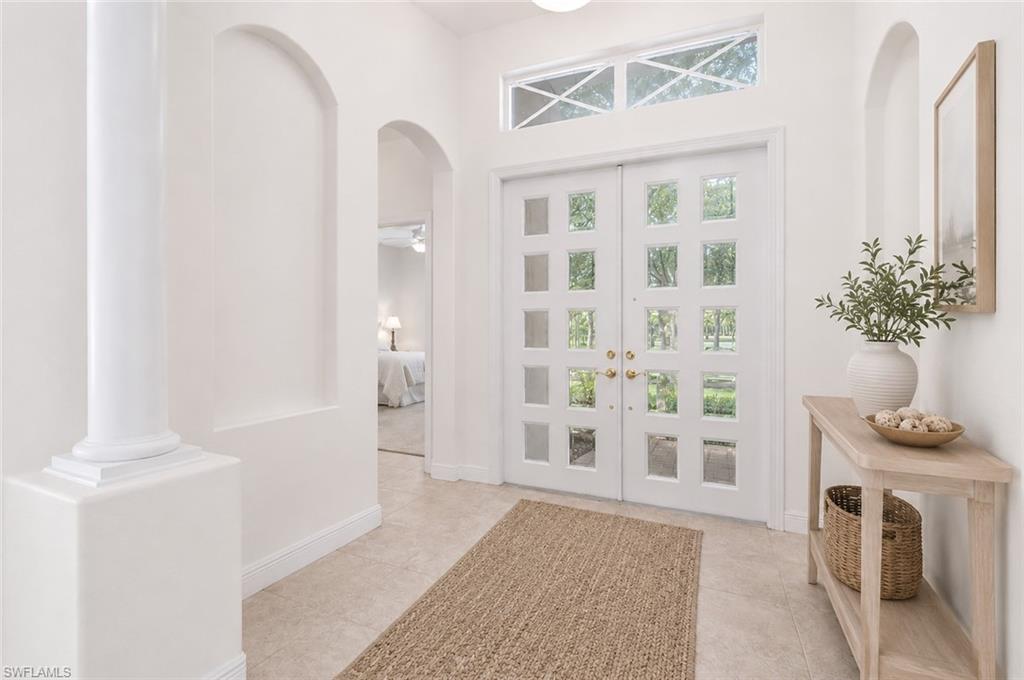 Photo shows home reimagined with white paint on walls, updated front doors and updated furnishings.  AI GENERATED