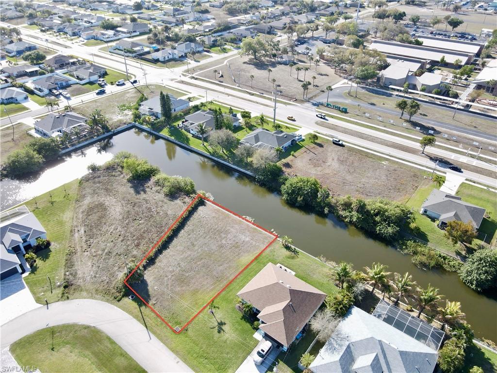 Aerial view of residential area featuring property boundaries highlighted and a nearby body of water