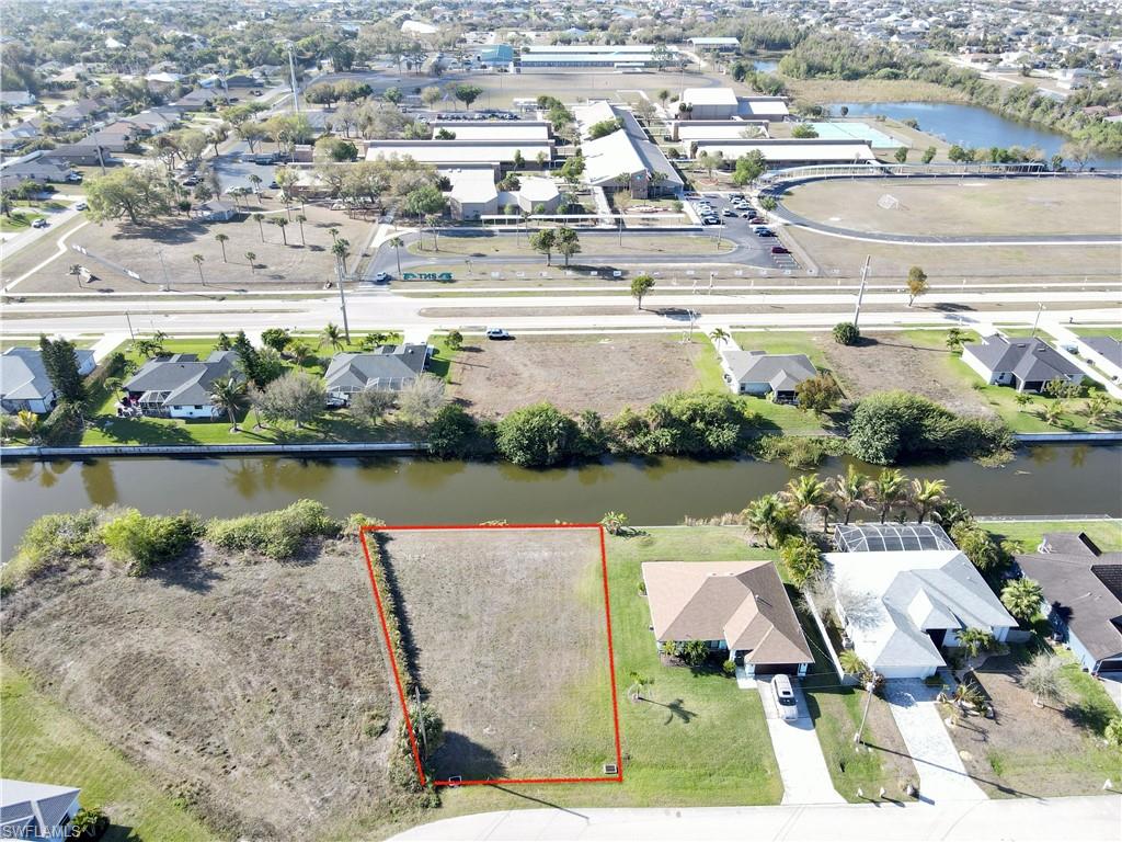 Aerial view of residential area featuring a nearby body of water and property parcel outlined