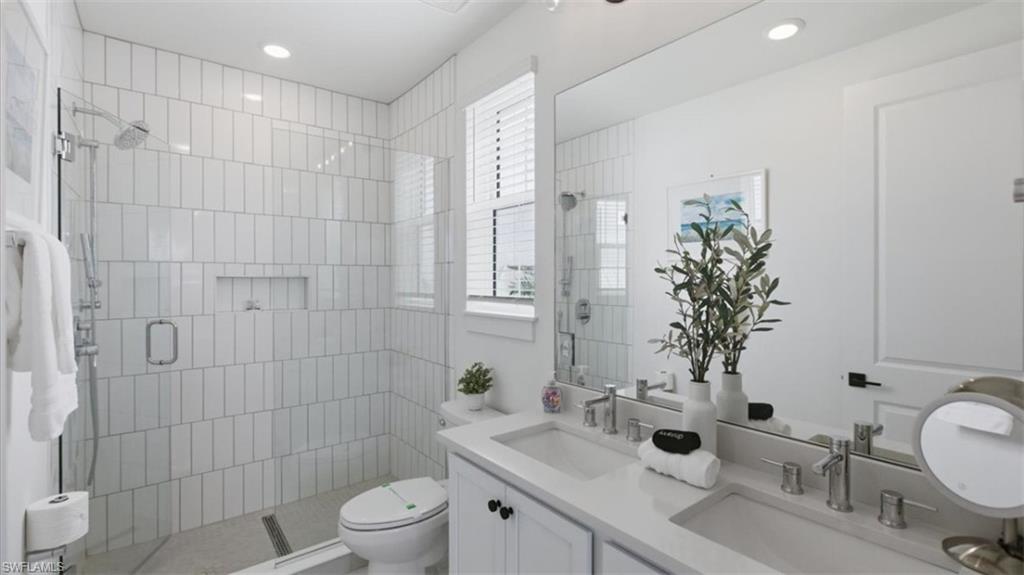 Full bath with double vanity, a stall shower, and recessed lighting - Virtually Edited