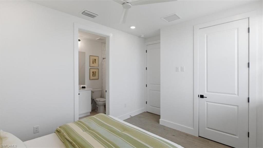Bedroom with light wood-type flooring, ensuite bathroom, and recessed lighting - Virtually Edited