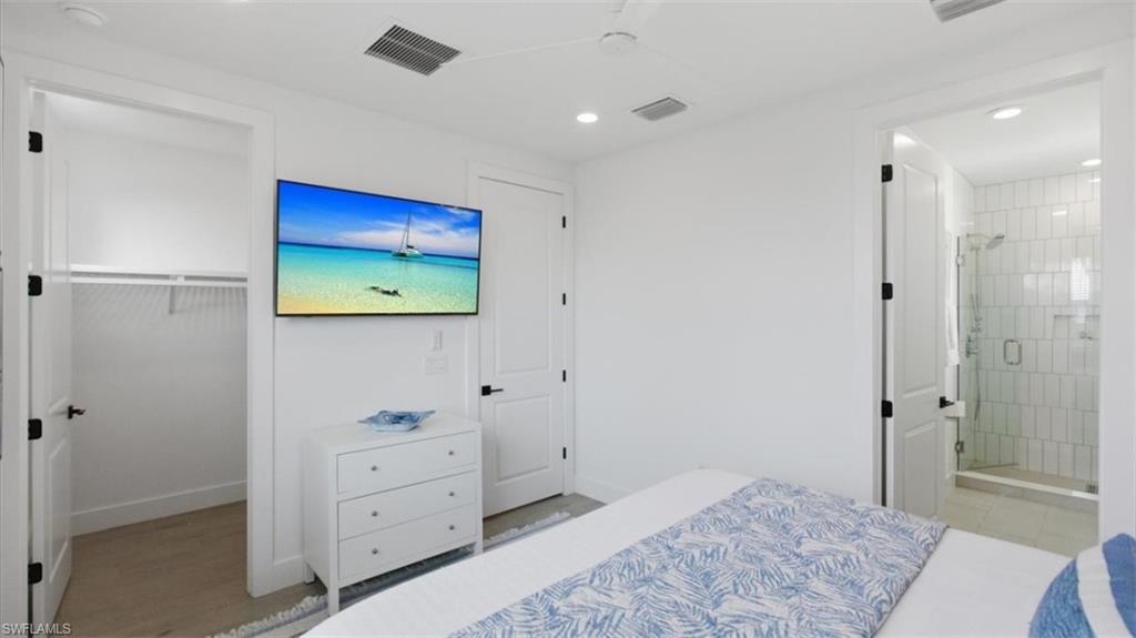 Bedroom with ensuite bath, recessed lighting, and light wood-style floors - Virtually Edited