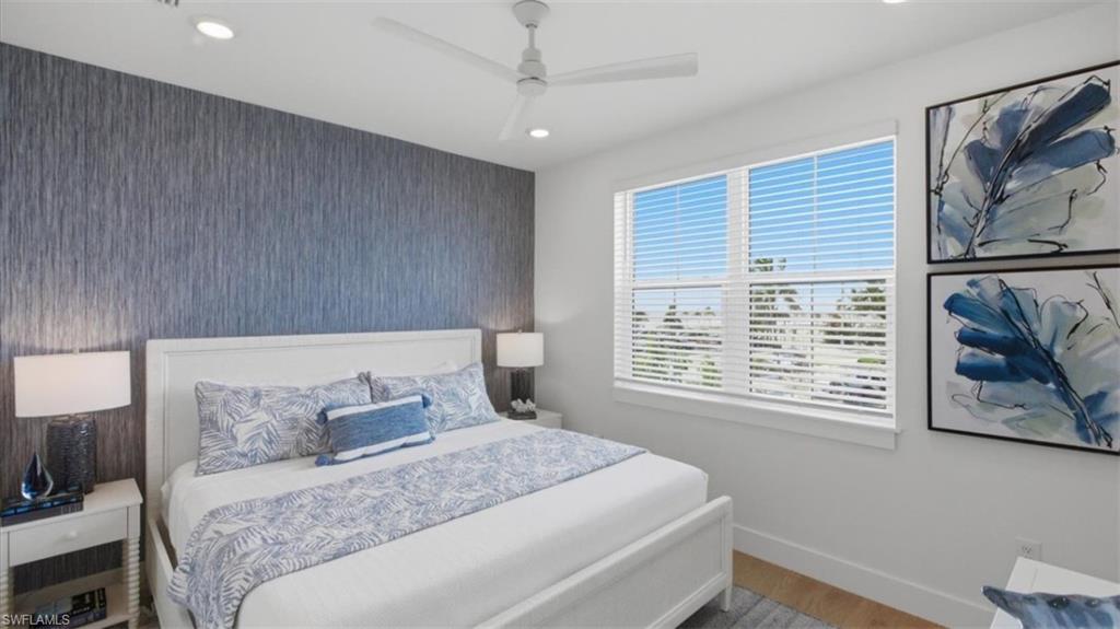 Bedroom featuring an accent wall, ceiling fan, wood finished floors, wallpapered walls, and recessed lighting - Virtually Edited