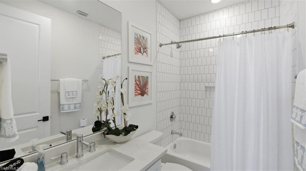 Bathroom with vanity and shower / bathtub combination with curtain - Virtually Edited