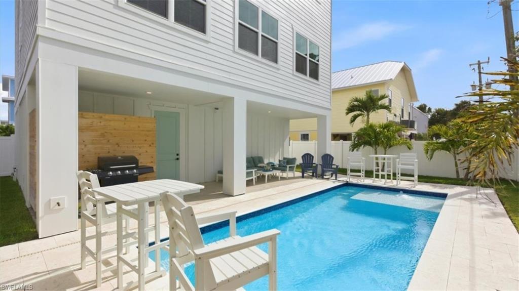 Back of property with a patio area, board and batten siding, a fenced backyard, and an outdoor pool- Virtually Edited