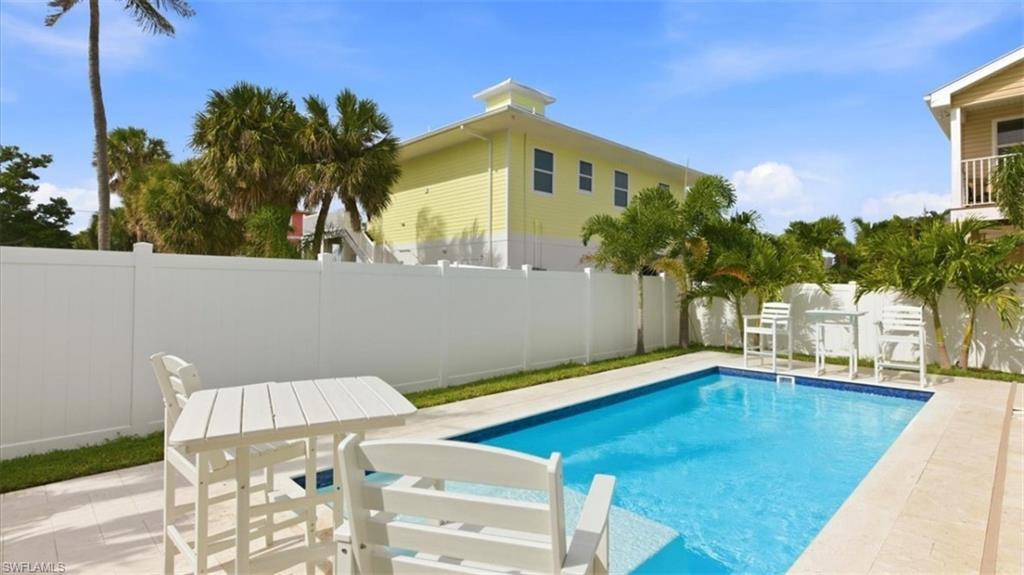 View of pool featuring patio surround, a fenced backyard, and outdoor dining space - Virtually Edited