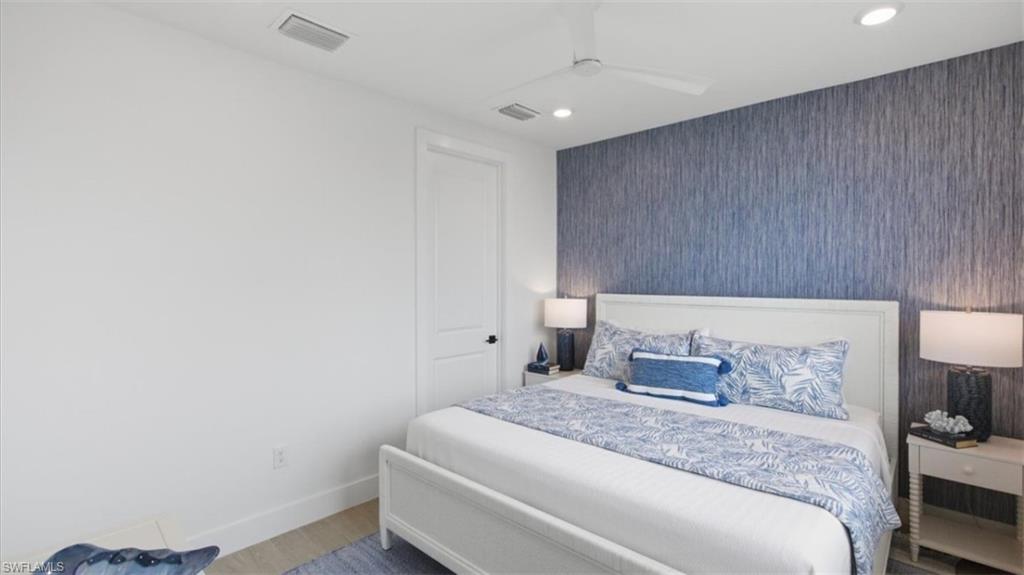 Bedroom with an accent wall, wallpapered walls, a ceiling fan, recessed lighting, and wood finished floors - Virtually Edited