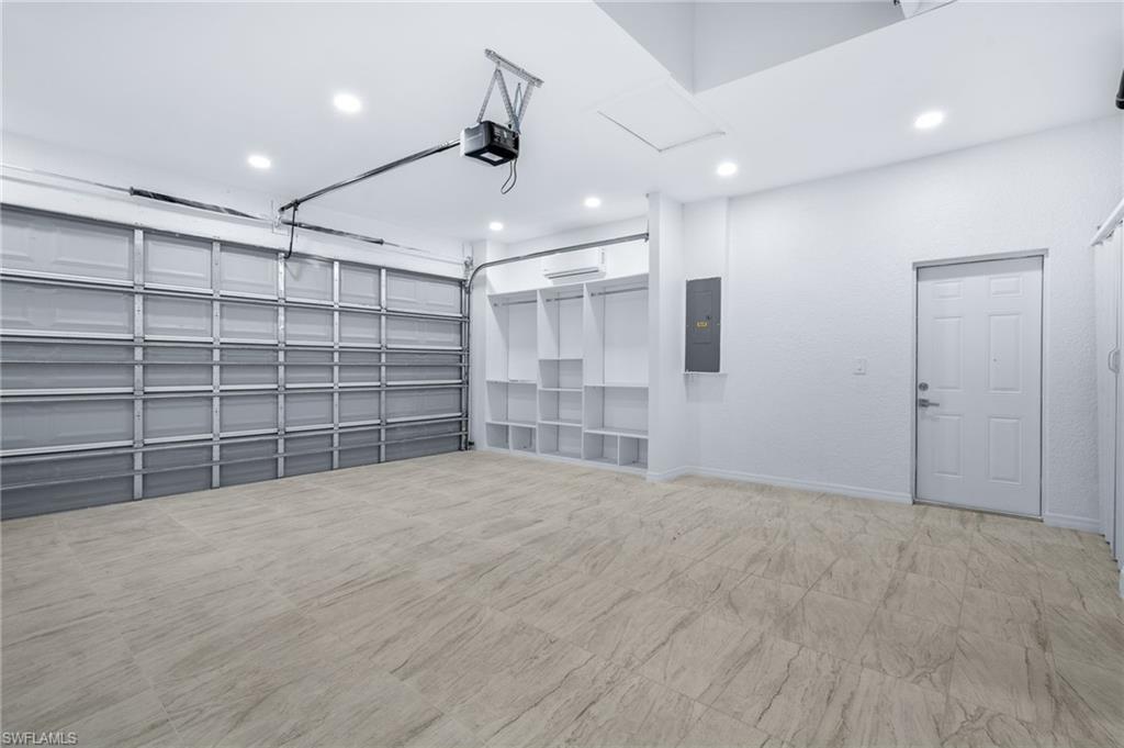 Garage with electric panel, recessed lighting, and a garage door opener