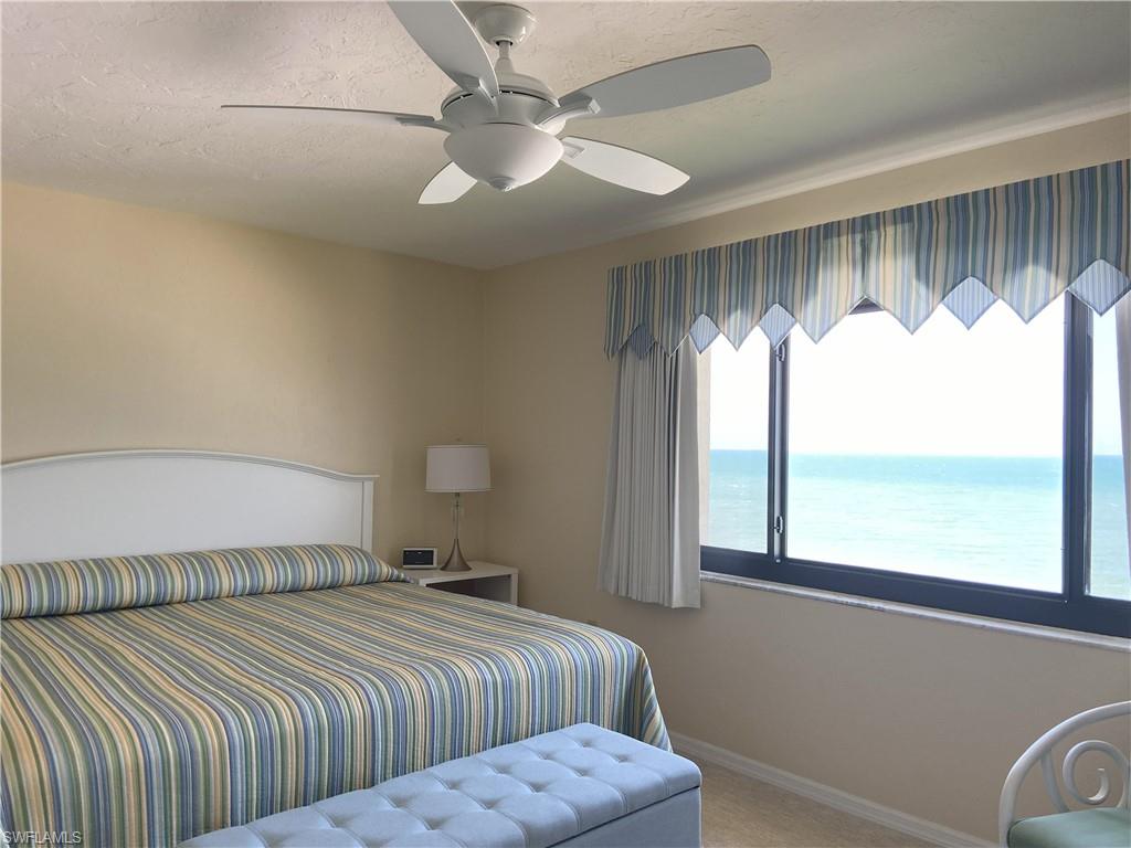 Carpeted bedroom featuring ceiling fan, a textured ceiling, a water view, and baseboards