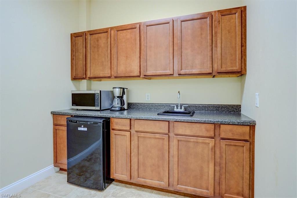 Kitchen with brown cabinetry, stainless steel microwave, and black fridge
