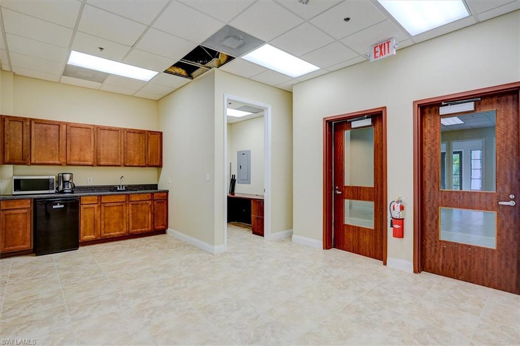 Kitchen featuring dishwasher, brown cabinetry, stainless steel microwave, a drop ceiling, and electric panel