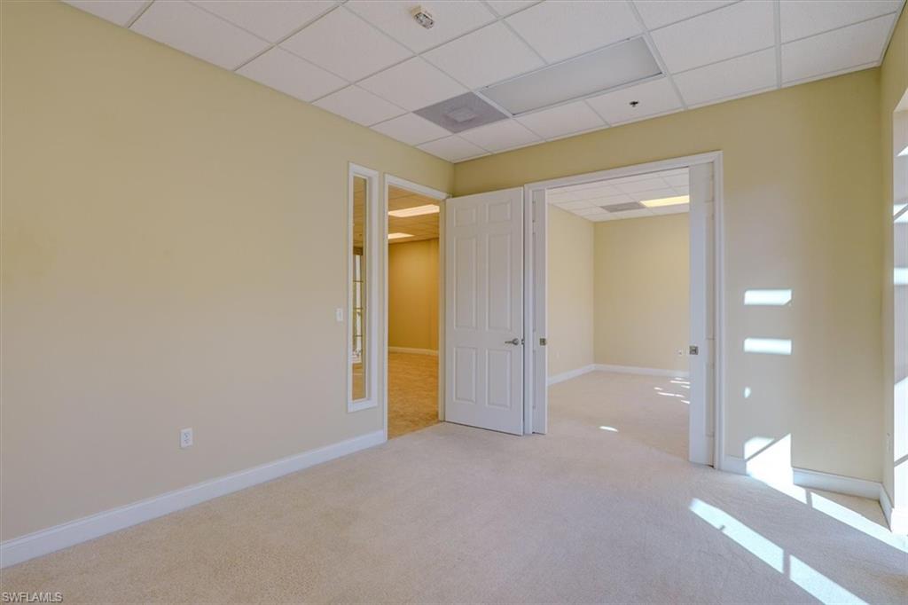 Carpeted office with a drop ceiling and baseboards