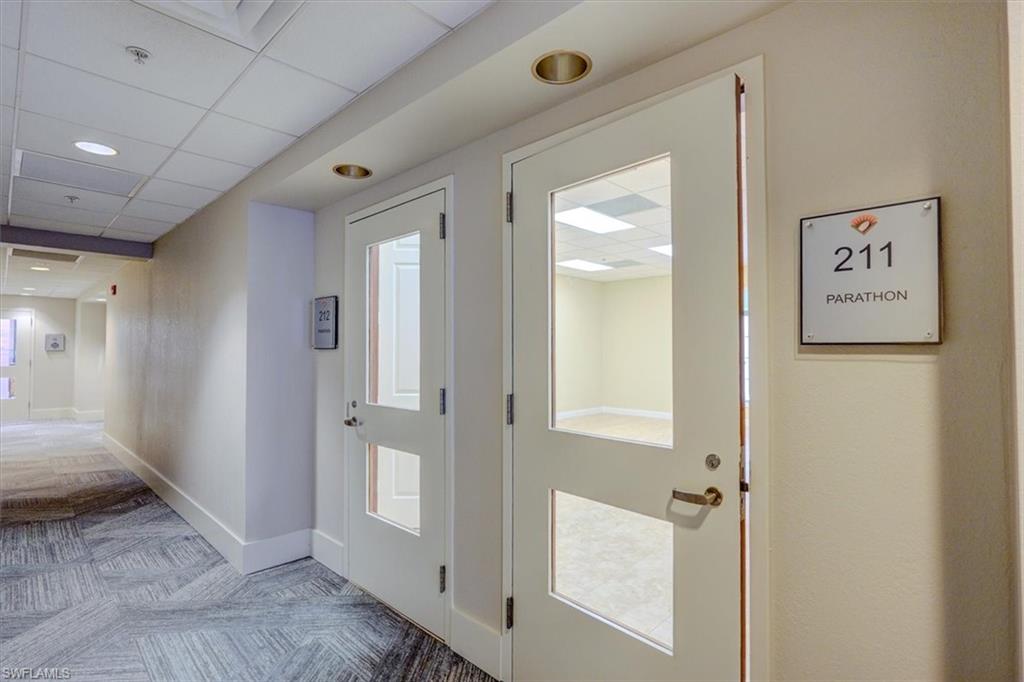 Common area hallway corridor with light carpet and a paneled ceiling