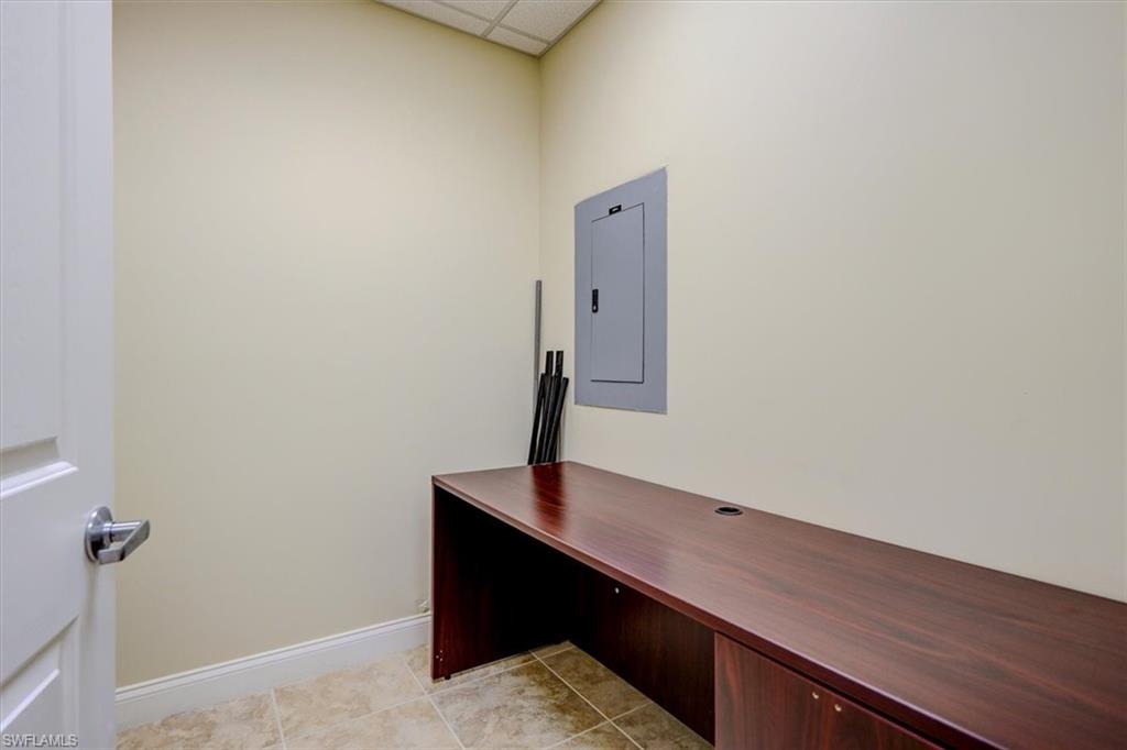Unfurnished office, tiled ceiling, electric panel, and light tile patterned floors