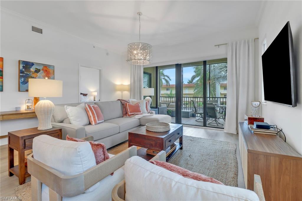 Living room featuring floor to ceiling windows, light hardwood / wood-style flooring, ornamental molding, and an inviting chandelier