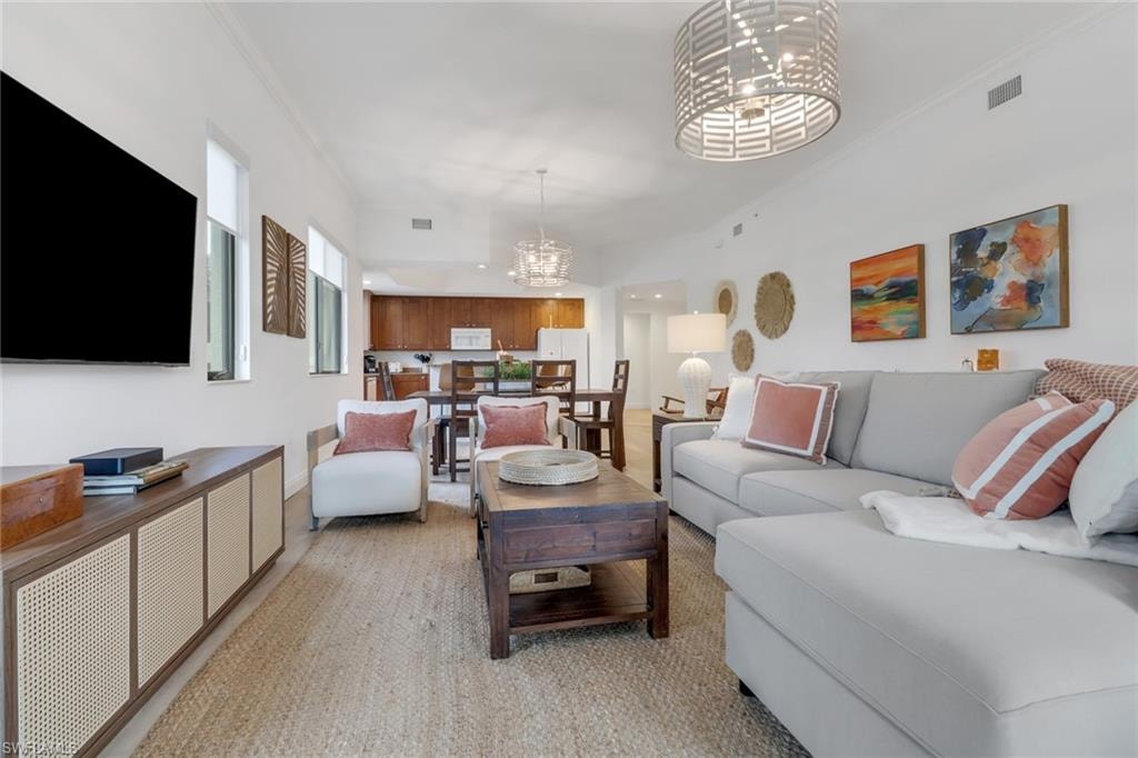 Living room featuring crown molding and an inviting chandelier