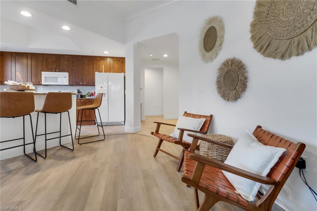 Kitchen with crown molding, white appliances, and light hardwood / wood-style flooring
