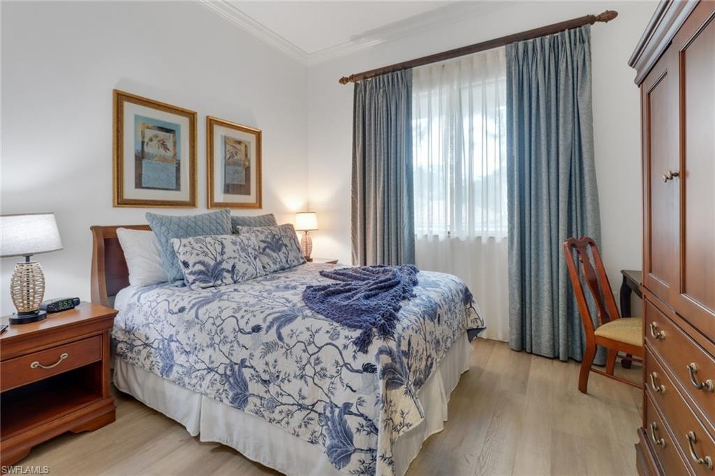 Bedroom with light hardwood / wood-style floors and ornamental molding