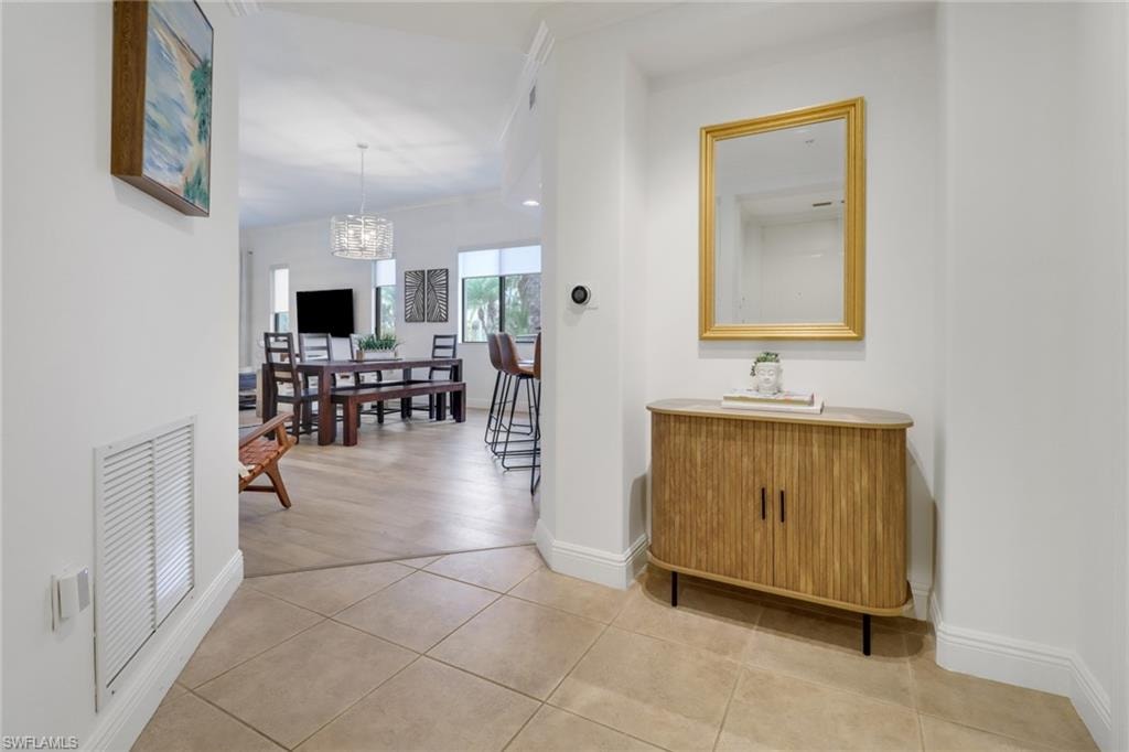 Hall with light tile patterned floors and a notable chandelier