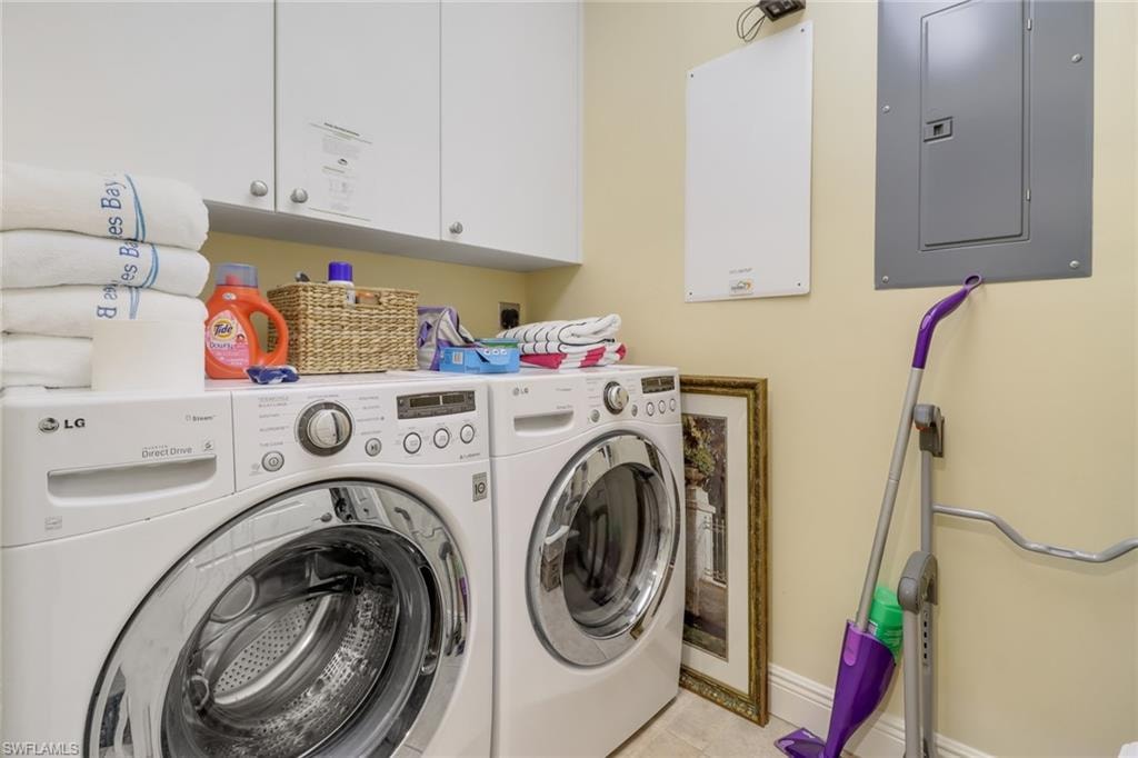 Laundry room featuring light tile patterned floors, cabinets, electric panel, and washing machine and clothes dryer