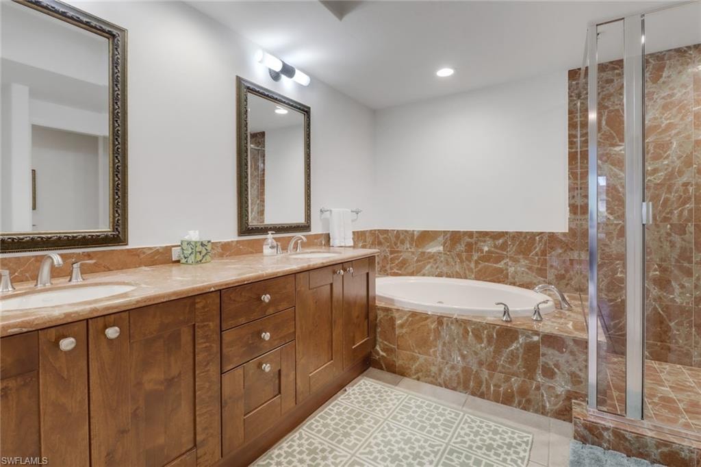Bathroom featuring tile patterned floors, vanity, and separate shower and tub