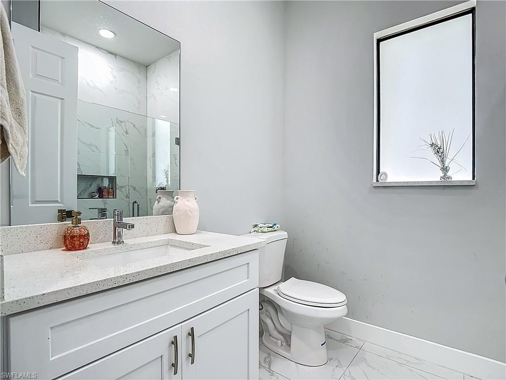 Full bathroom featuring a marble finish shower, vanity, and light marble finish flooring