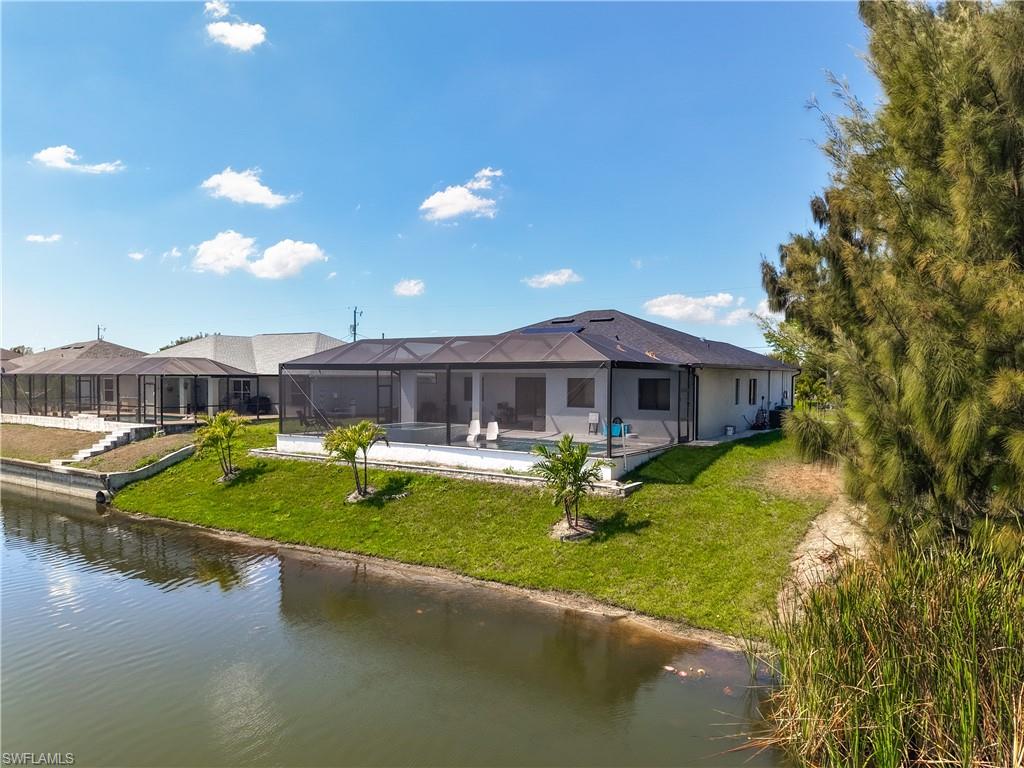 Rear view of property with a water view, a sunroom, a yard, a pool, and glass enclosure